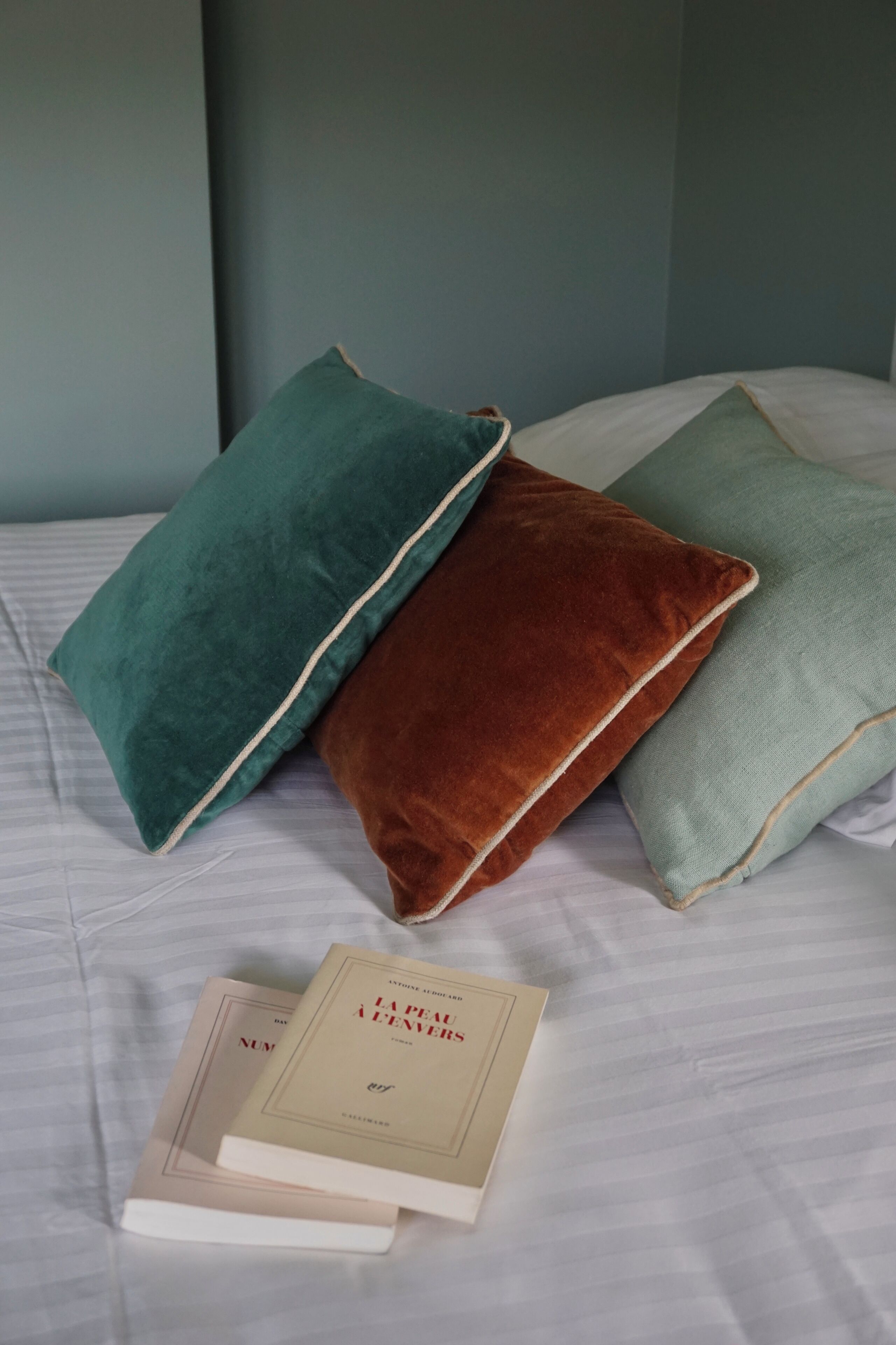 A bed with three pillows and two books.