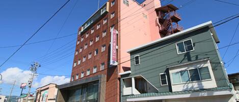 A multi-story building with a parking sign, a modern building with large windows, and a smaller building with a garage.