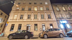 A building with multiple windows and doors, parked cars in front, and a bicycle to the left.