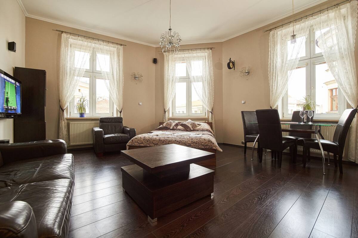 A spacious living room with a large bed, a coffee table, and a dining area with chairs and a table.