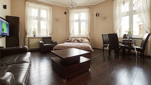 A spacious living room with a large bed, a coffee table, and a dining area with chairs and a table.