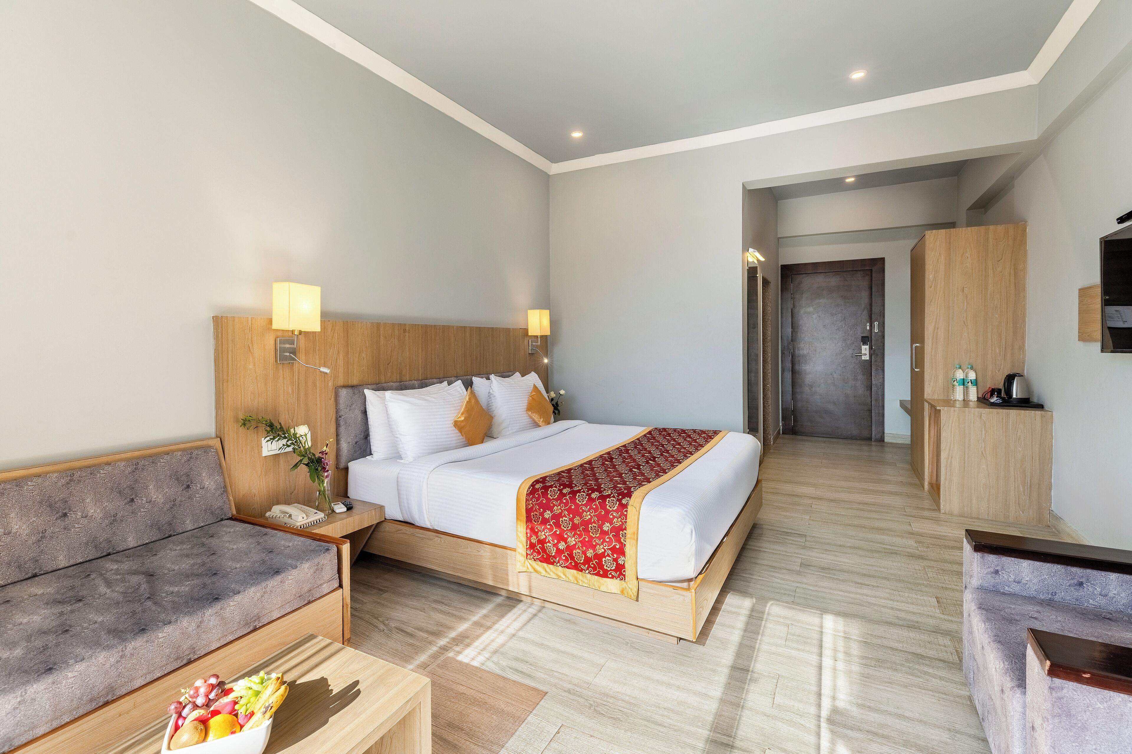 Una habitación de hotel con cama, sofá, escritorio y una kitchenette pequeña.