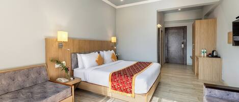 Una habitación de hotel con cama, sofá, escritorio y una kitchenette pequeña.