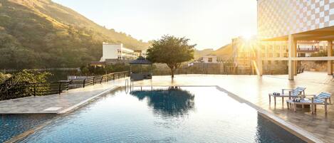 A swimming pool with a view of a mountain and a building with a checkered facade.