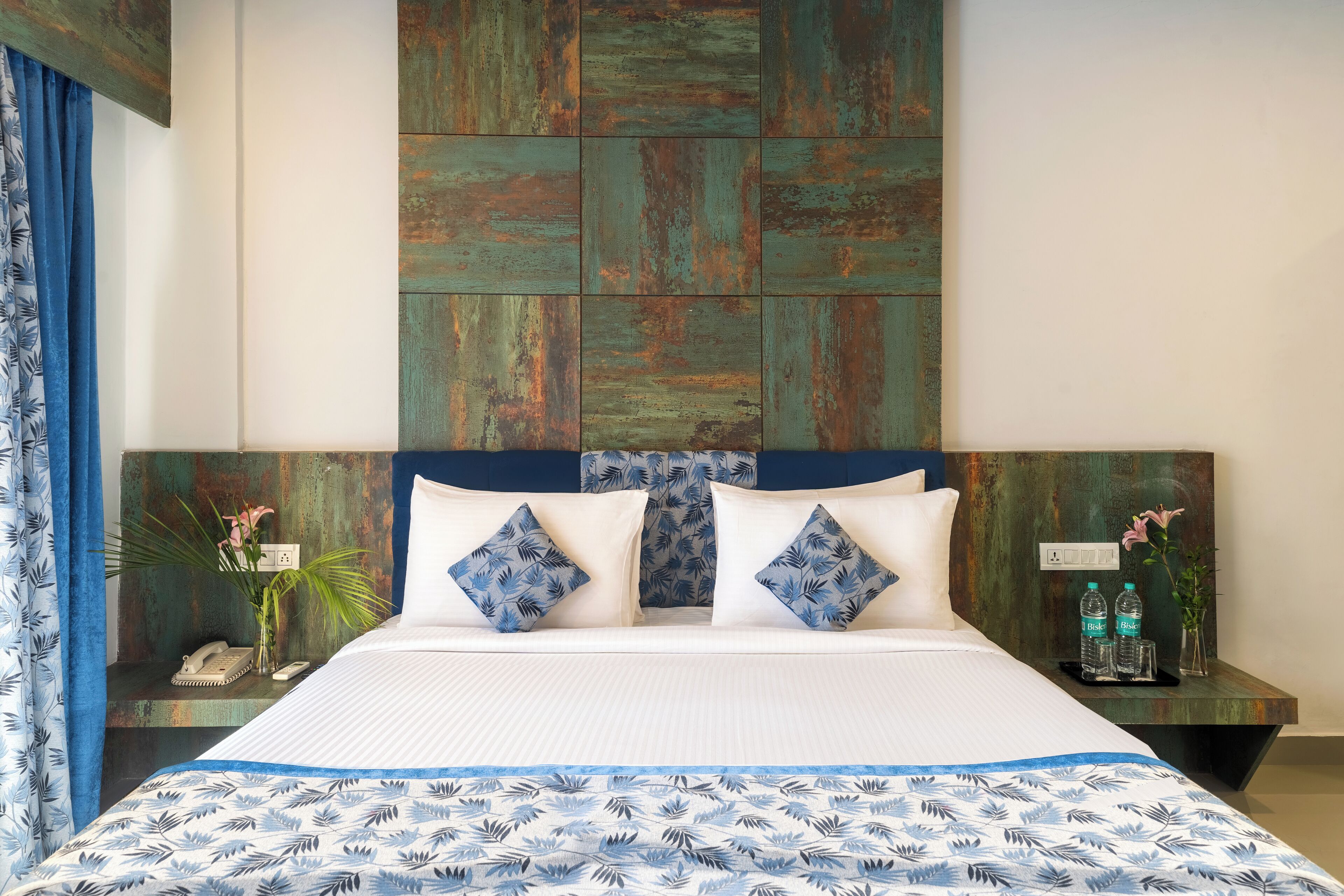 A hotel room with a bed, a headboard, a nightstand, and a wall-mounted telephone.
