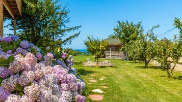 A garden with a wooden structure, a lawn, and a view of the sea.