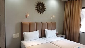 A hotel room with a large bed, two bedside tables, a wall-mounted light fixture, and a window with curtains. - Landmark Asia Serviced Apartments (Mumbai)