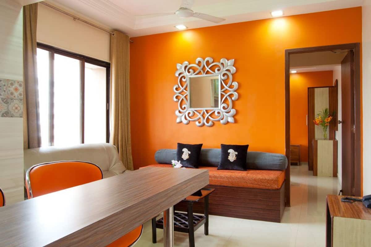 A modern living room with a sofa, a dining table, and a decorative mirror.
