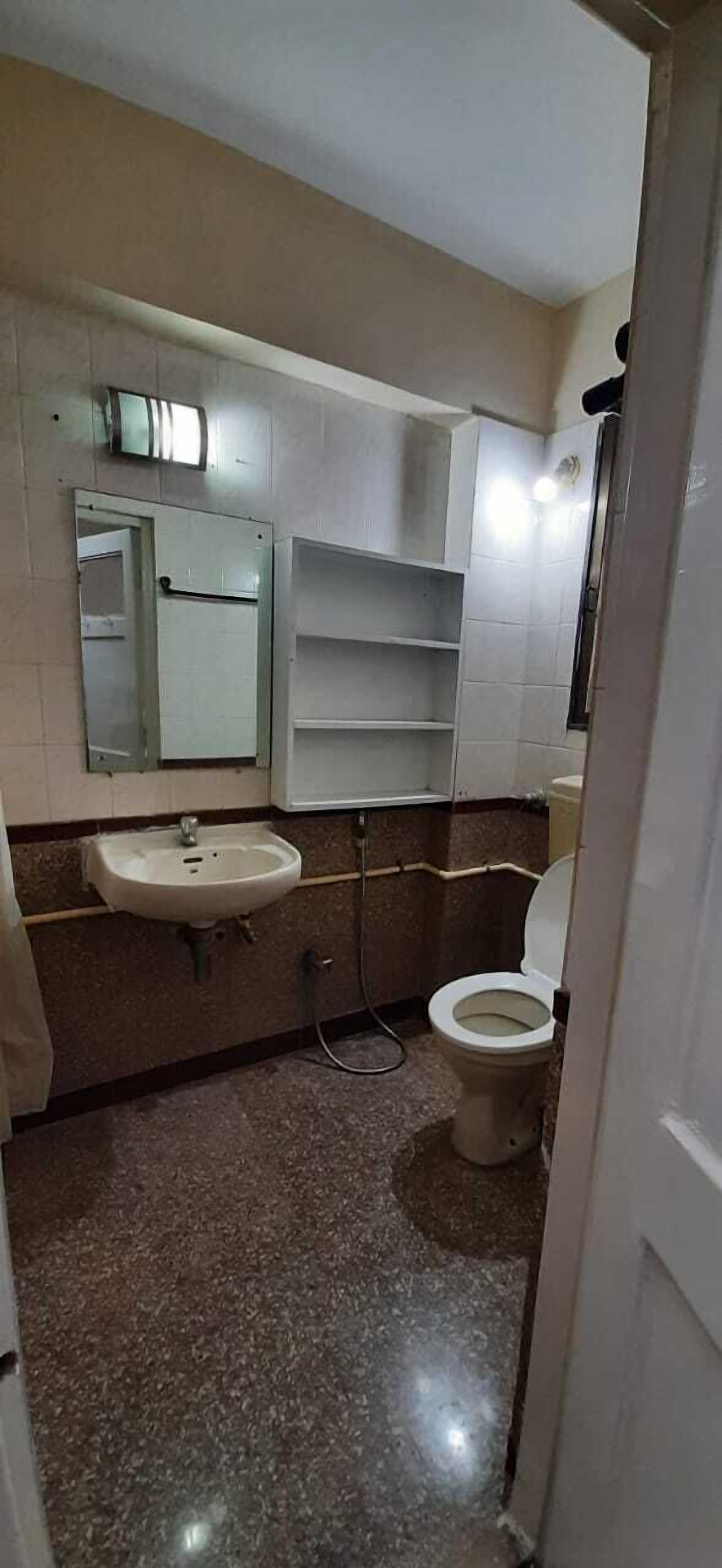 Egy fürdőszoba, amelyben mosdókagyló, WC és polcok találhatók.
