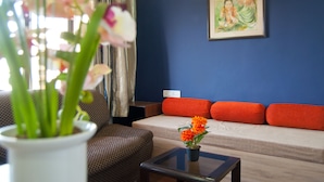 A living room with a sofa, a small table, a potted plant, and a painting on the wall. - Landmark Asia Serviced Apartments (Mumbai)