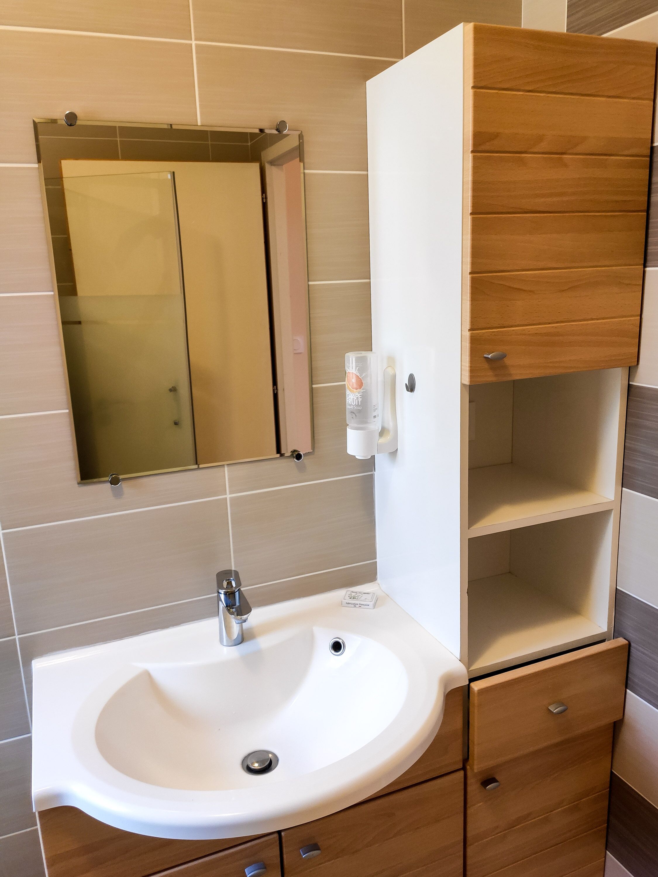 A bathroom with a white sink, a mirror, and a wooden cabinet with drawers.