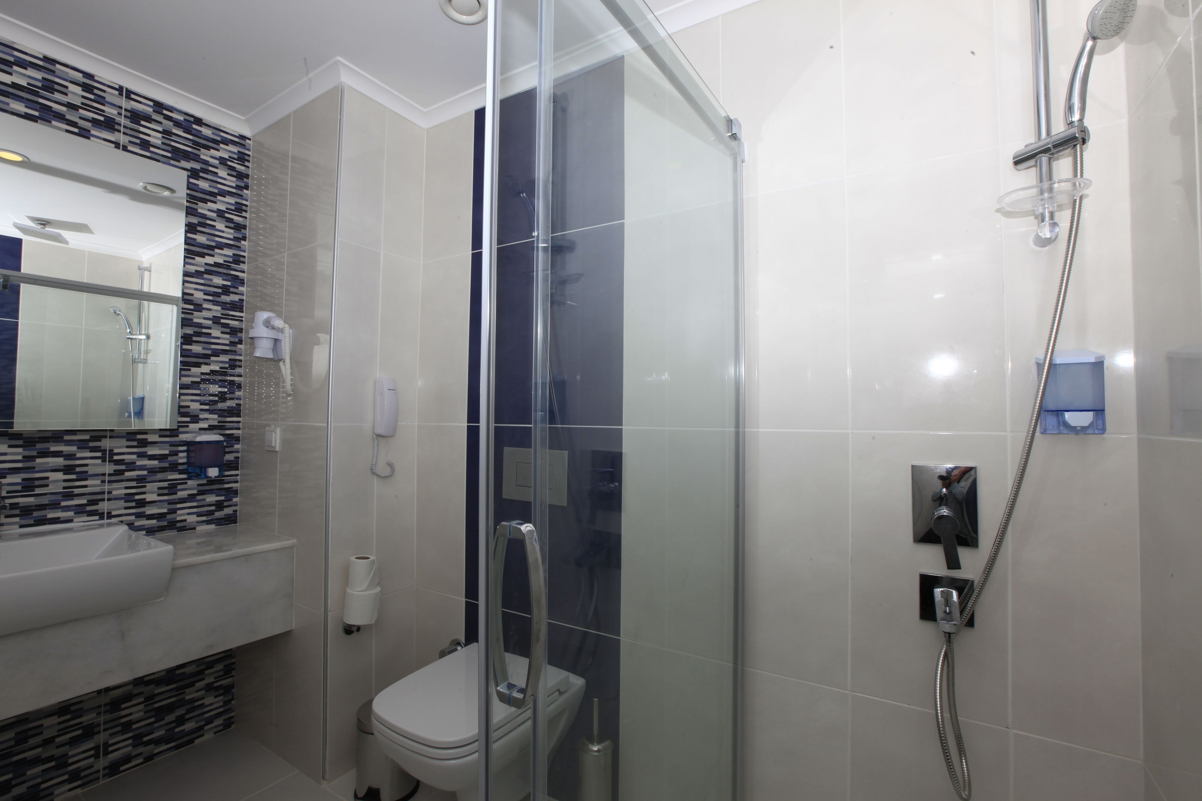A modern bathroom with a glass-enclosed shower, a white sink, and a tiled backsplash.