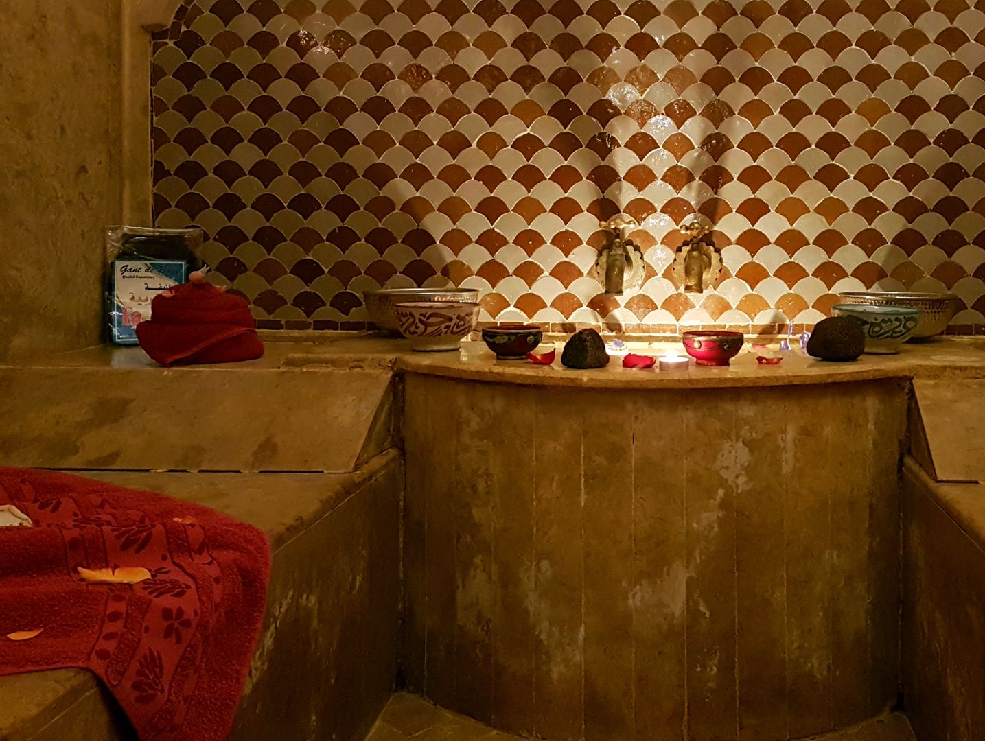 A bathroom with a tiled wall, a sink, and various toiletries.