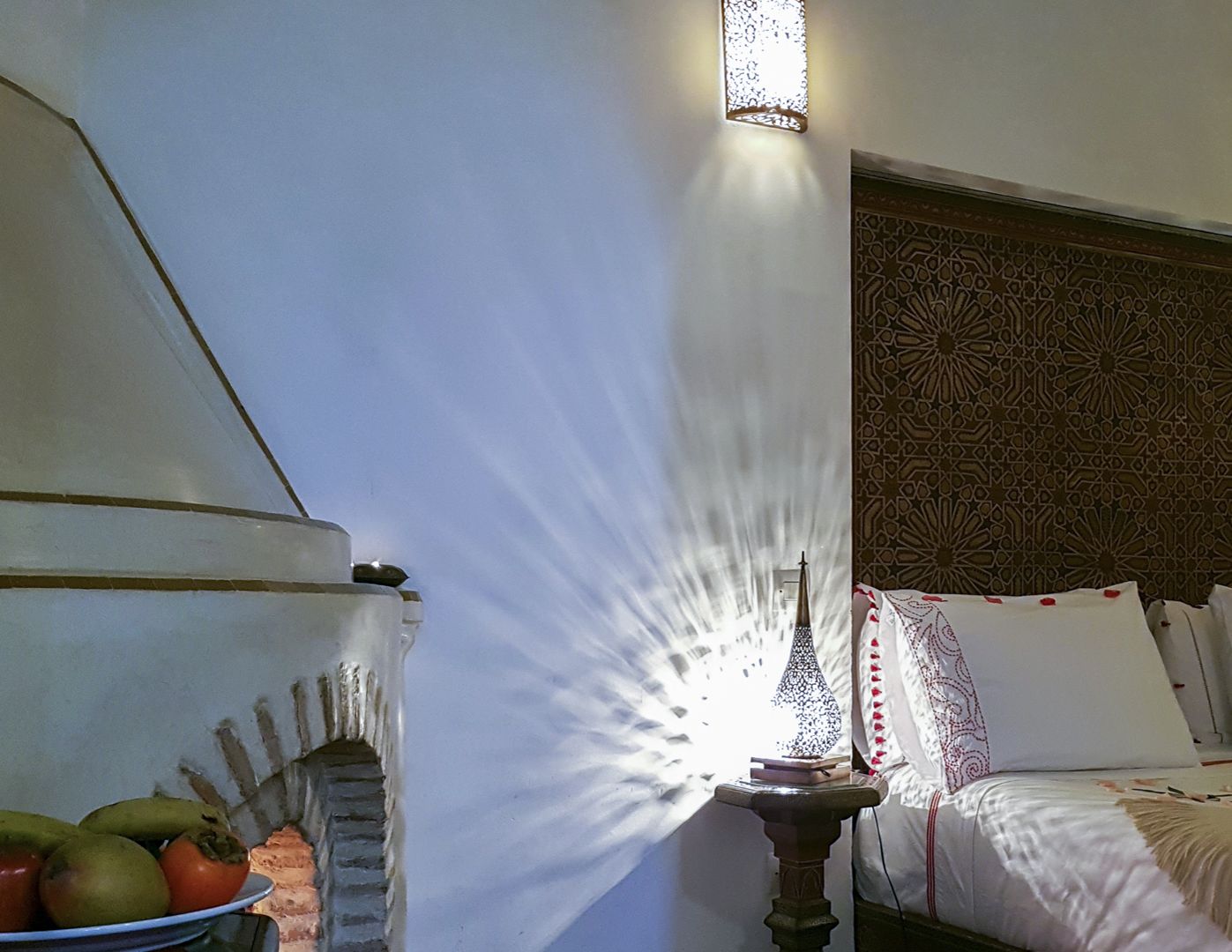 Una habitación con una cama, un muro decorativo y un aplique de pared.