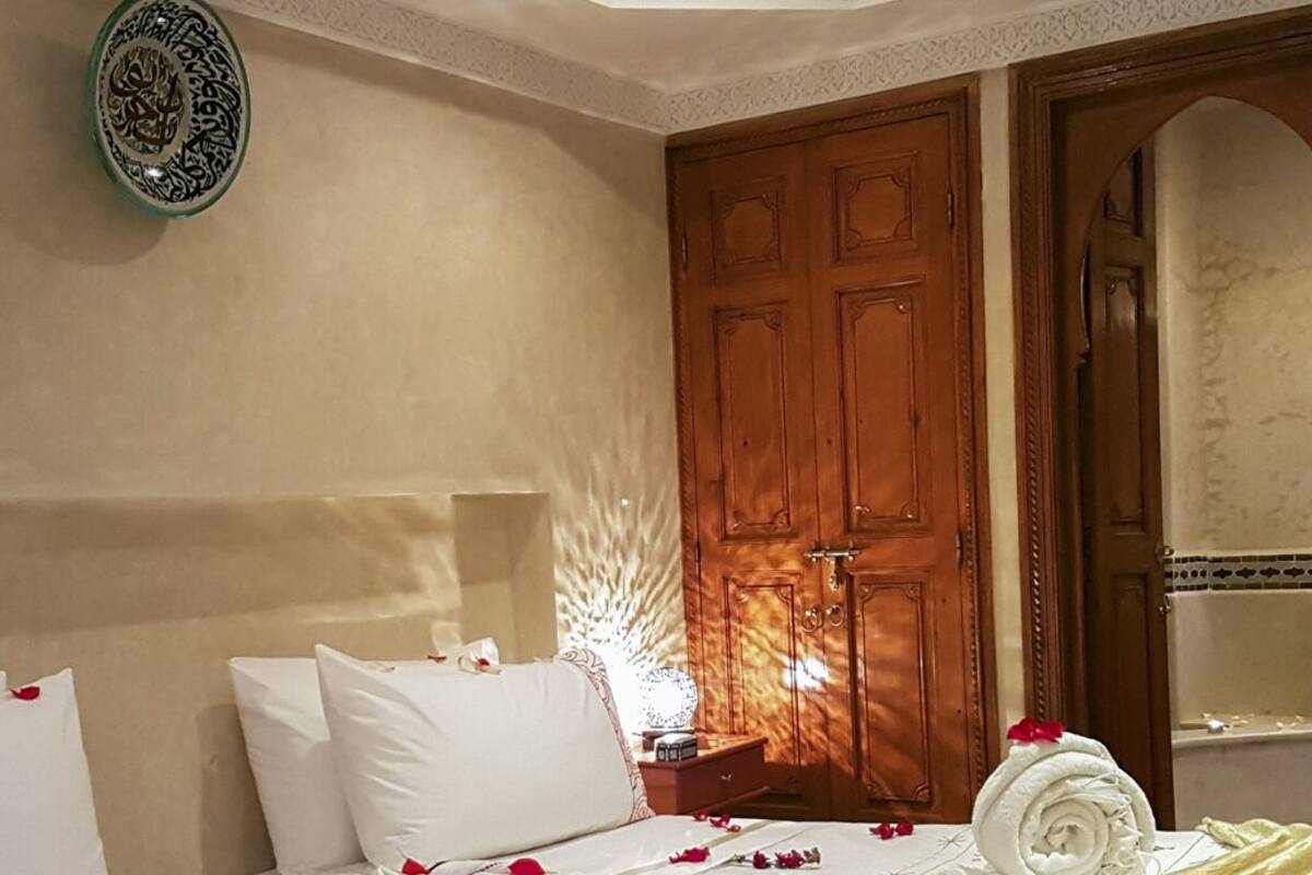 Un dormitorio con una cama, una mesita de noche, un adorno en la pared y una puerta de madera.