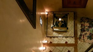 Una escalera con piso estampado, un espejo y una lámpara fijada a la pared.