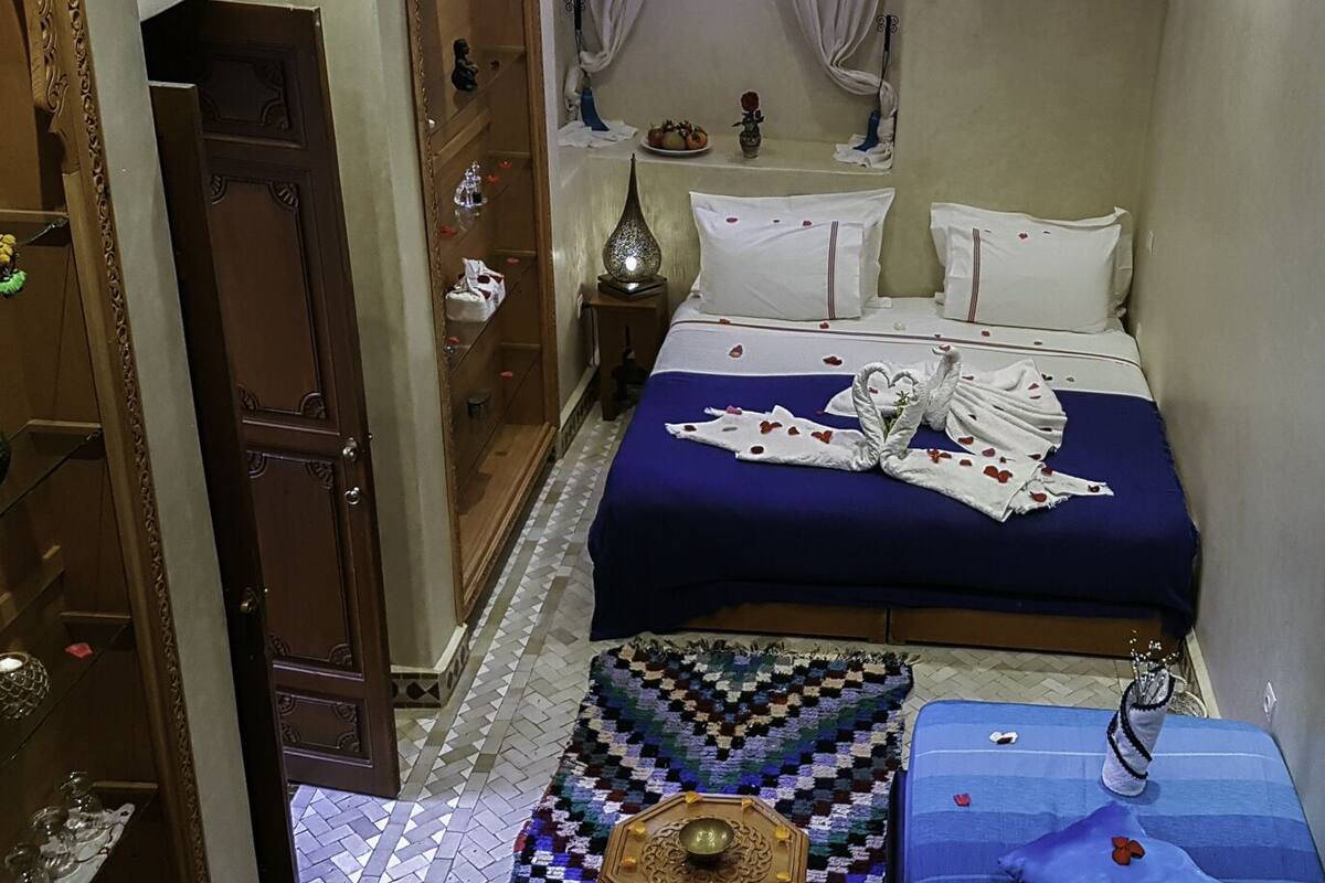 Una habitación de hotel con una cama, una mesita de noche, un aparador y una alfombra estampada.