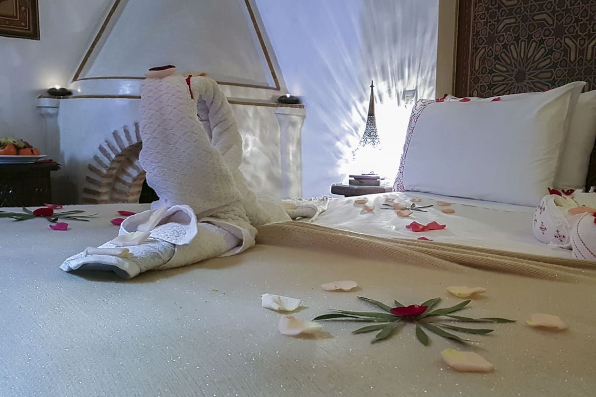 Una habitación de hotel con una cama bien hecha, un muro decorativo y una pequeña mesa con una lámpara.