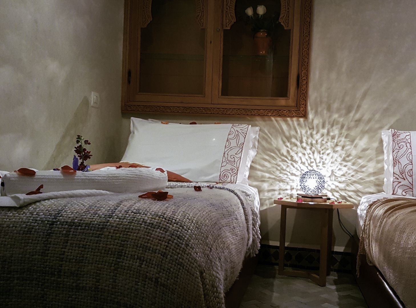 A bedroom with a bed, a nightstand, and a window with a decorative view.
