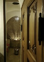 Um corredor estreito com parede revestida de azulejos e porta com puxador decorativo.