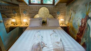 A double bed with two white towels, a round wall clock, and a mural on the wall.