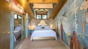Ein Schlafzimmer mit einem großen Bett, einer Wandmalerei und einer Holzbalkendecke.