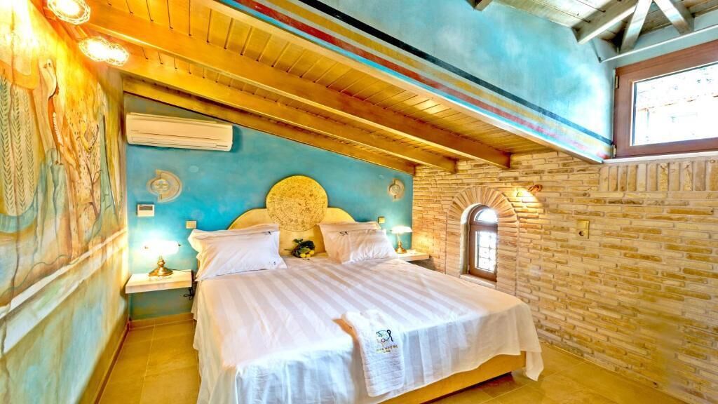 A room with a bed, a wall mural, a window, and a brick wall.