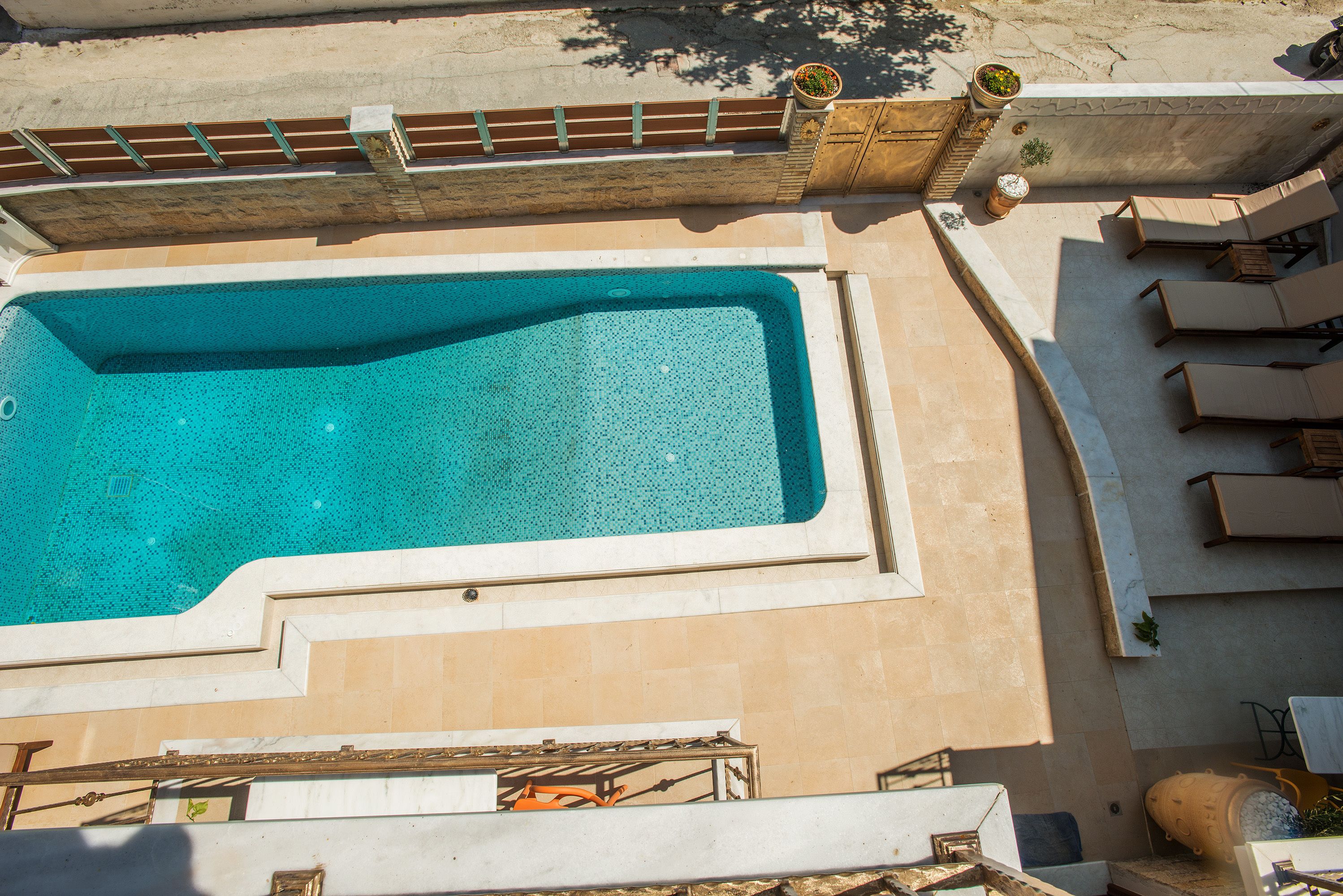 A rectangular swimming pool with a tiled deck surrounding it.