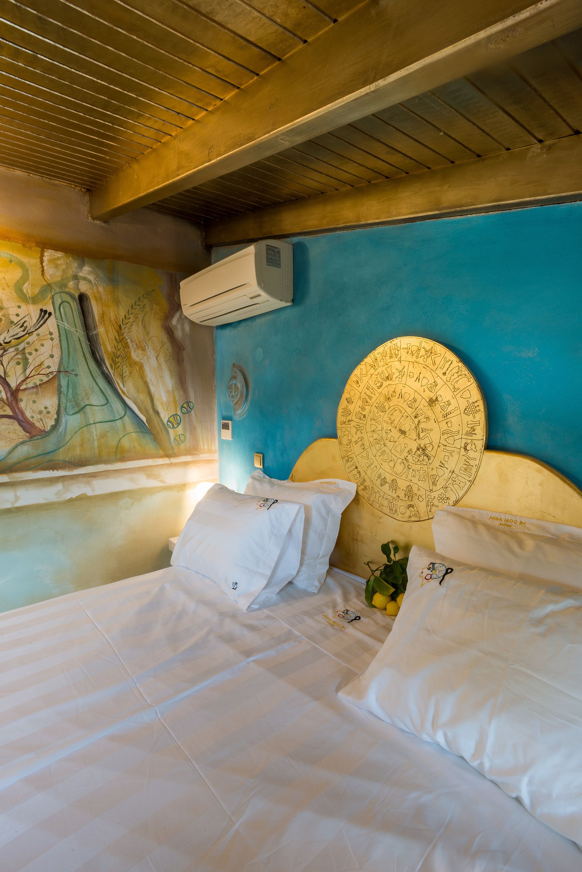 A room with a bed, a mural on the wall, and a circular object on the headboard.