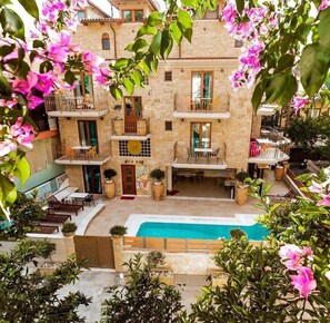 A multi-story building with balconies, a swimming pool, and outdoor seating areas. - Leda suites (Parga)