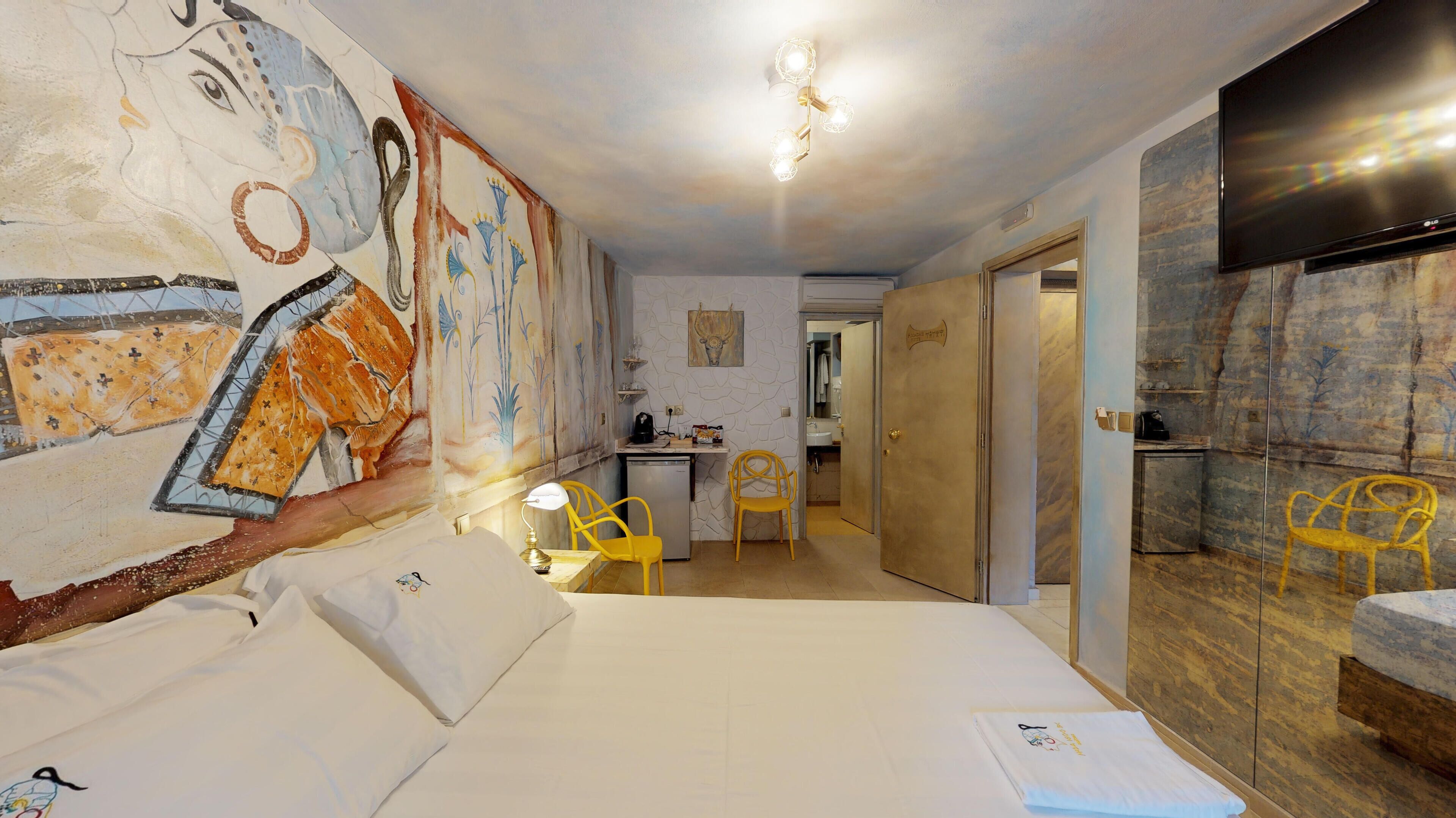 A hotel room with a bed, a desk, a chair, a bathroom, and a TV.