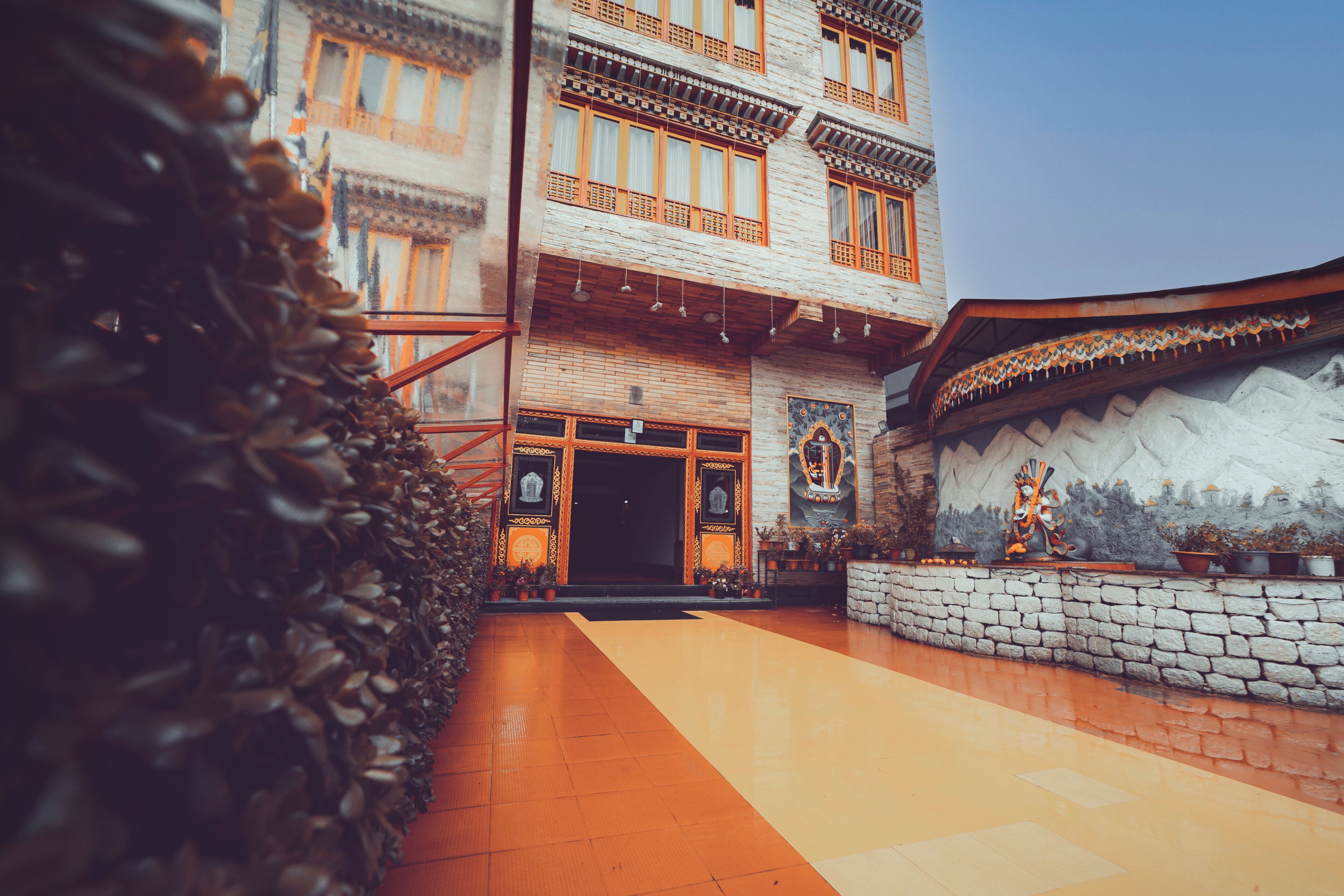 A traditional building with a stone facade, multiple windows with wooden frames, and a tiled entrance area.