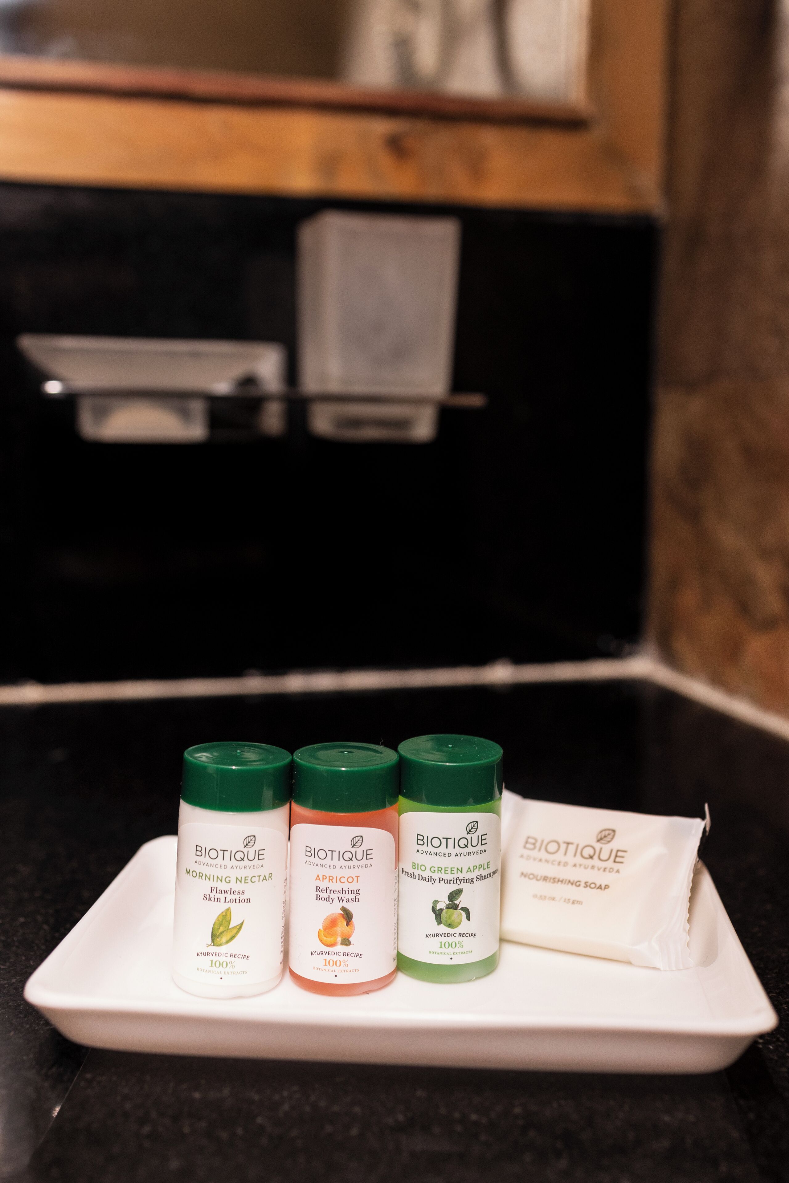 A white tray with three Biotique products and a bar of soap on a black countertop.