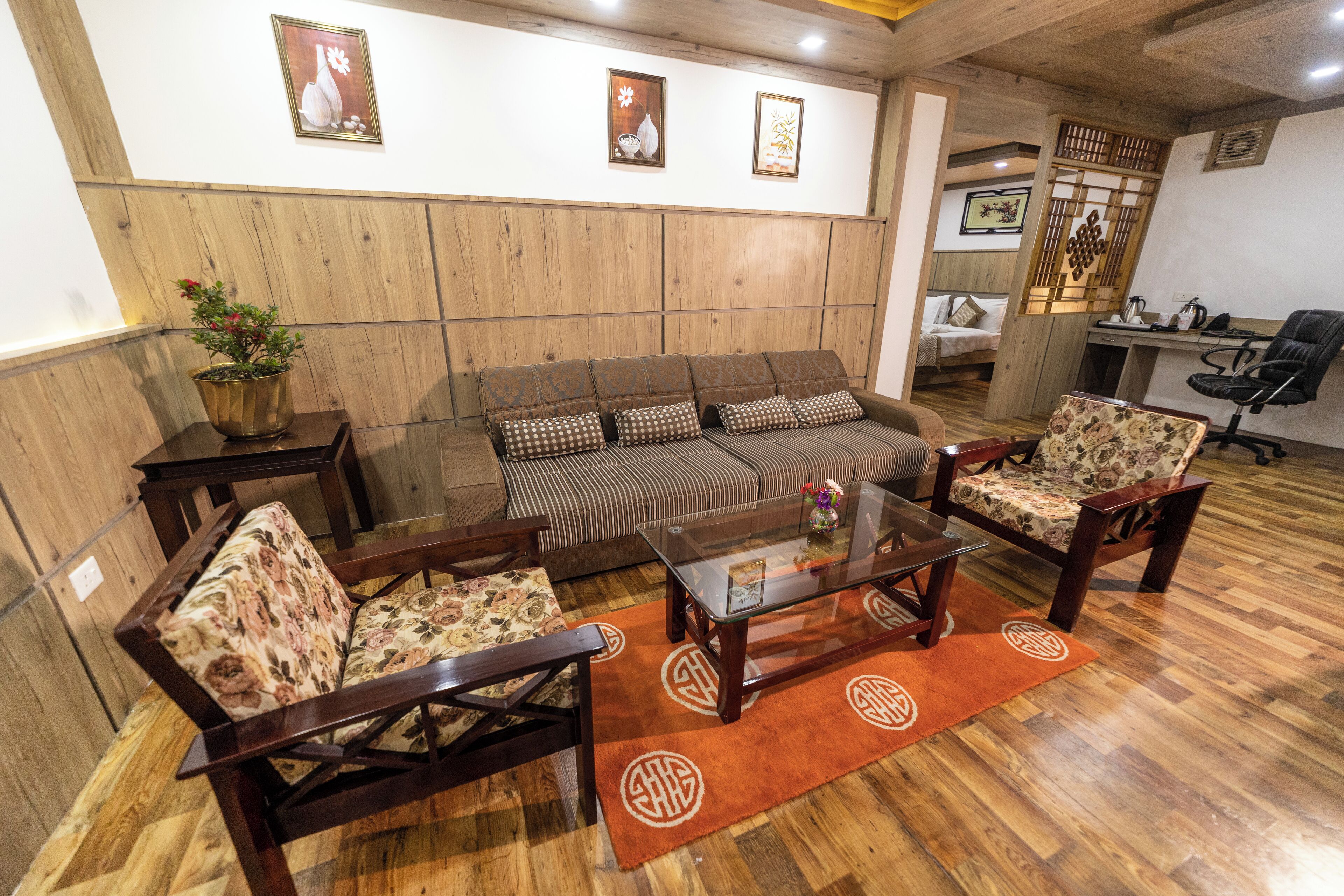 A cozy living area with a sofa, armchairs, a coffee table, and a wooden floor.