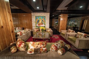 Uma área de estar aconchegante com sofás e poltronas estampadas com flores, uma mesa de centro e um grande quadro decorativo na parede.