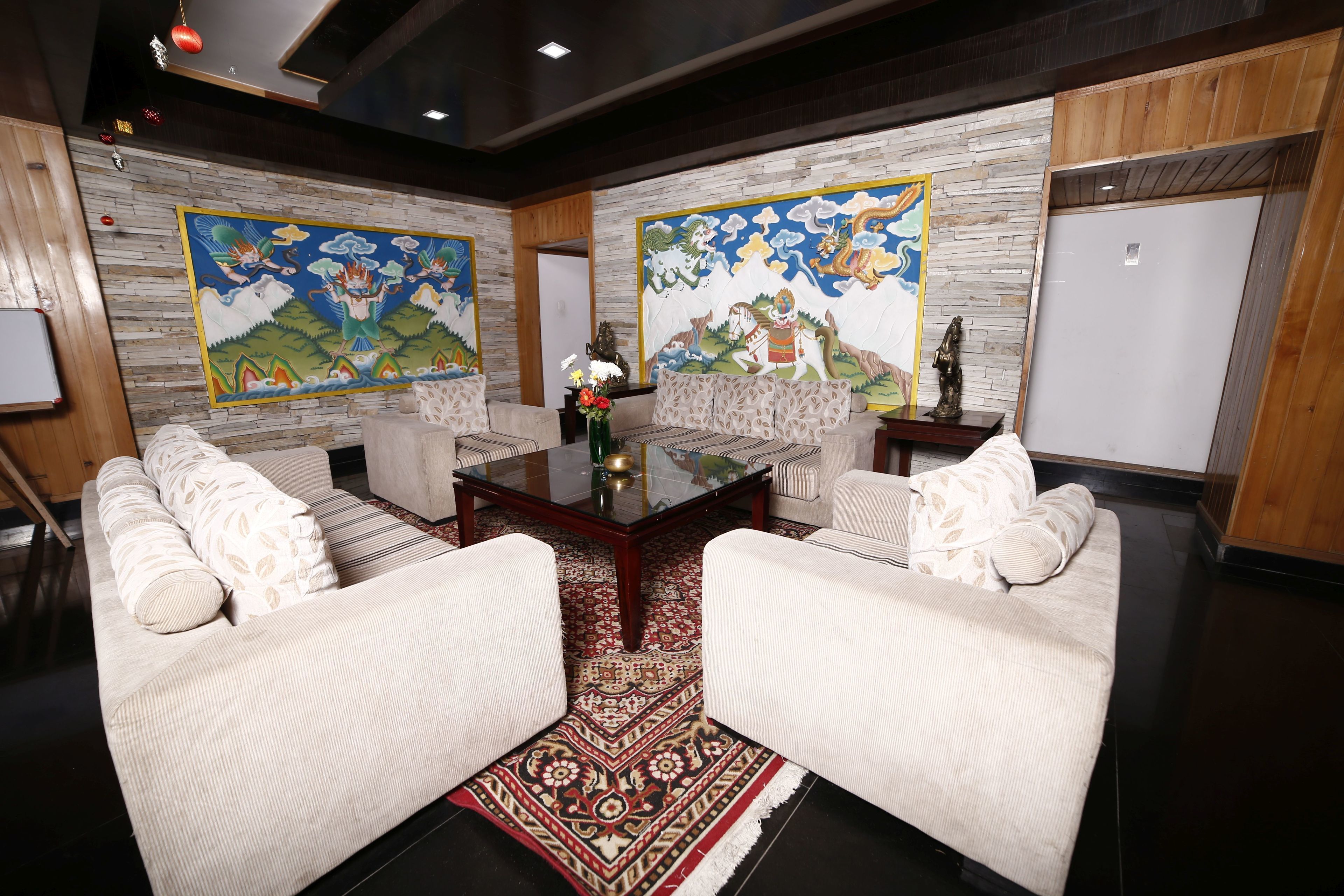 Une pièce avec deux canapés blancs, une table basse en verre et un tapis à motifs.