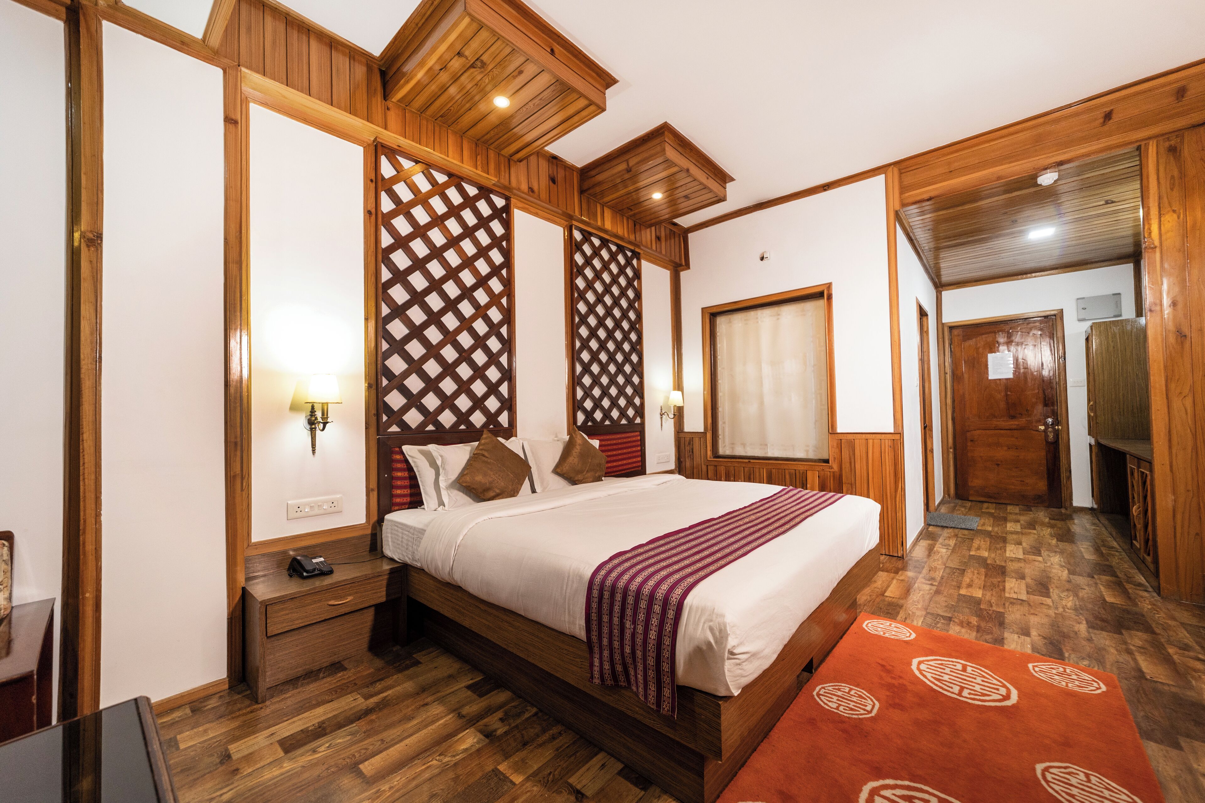 A bedroom with a wooden bed, a nightstand, a bedside table, and a wooden wardrobe.