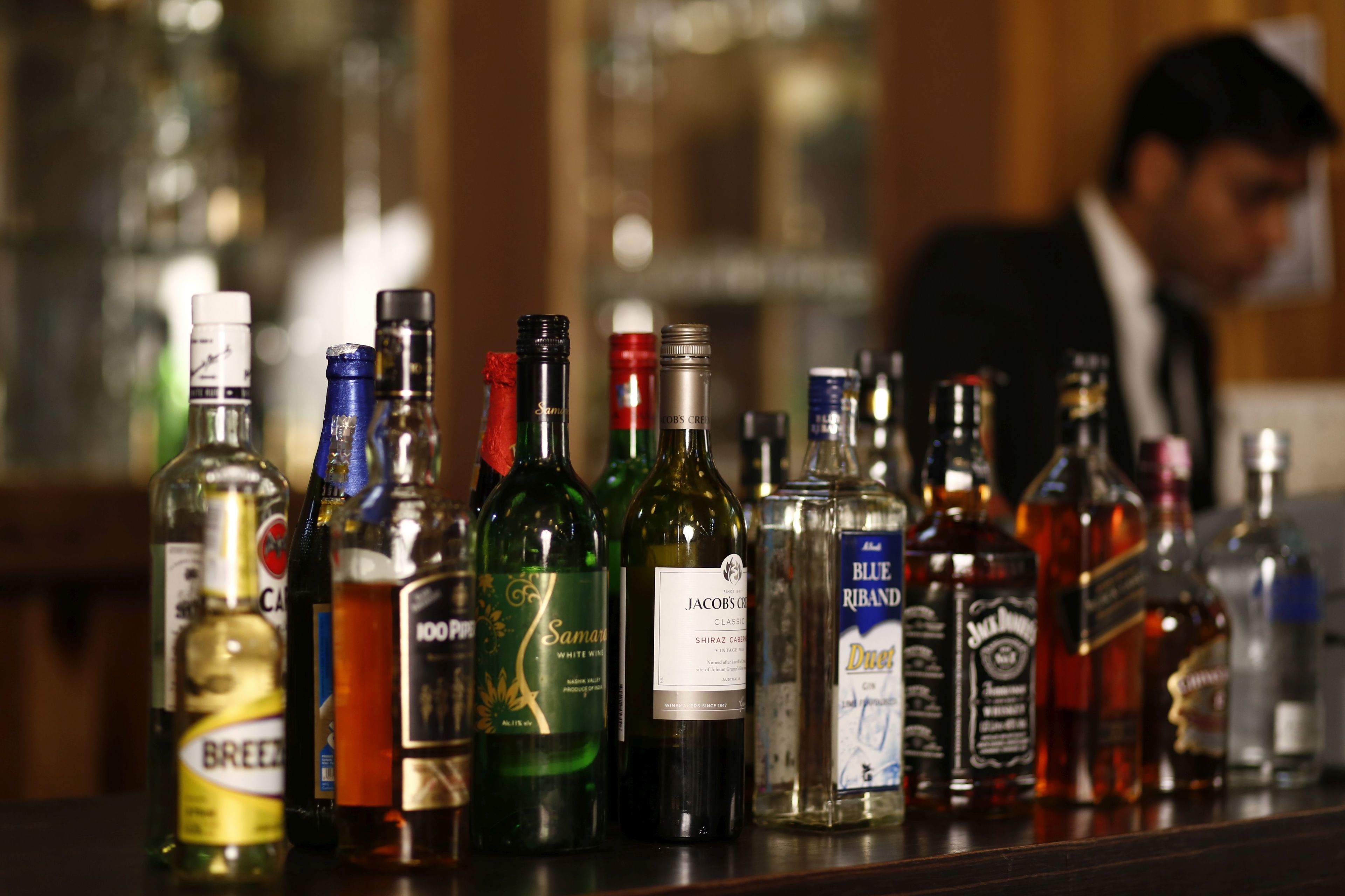 On peut voir une variété de bouteilles de spiritueux sur le comptoir d’un bar.