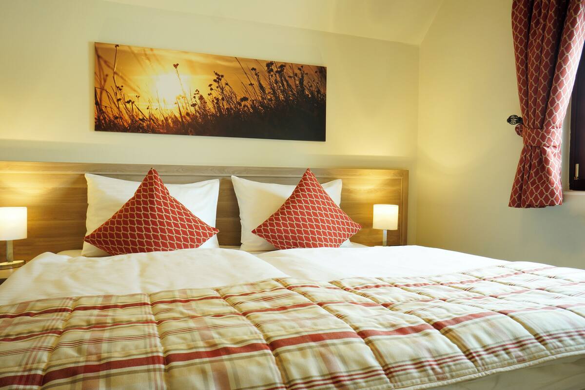 Een hotelkamer met een groot bed, twee bedlampjes, een hoofdeinde en een schilderij aan de muur.