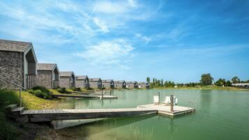 A lakeside hotel with a dock extending into the water, surrounded by stone buildings with pitched roofs.