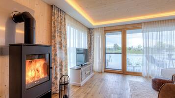 A modern living room with a wood-burning stove, a TV, and a large sliding glass door leading to an outdoor area.