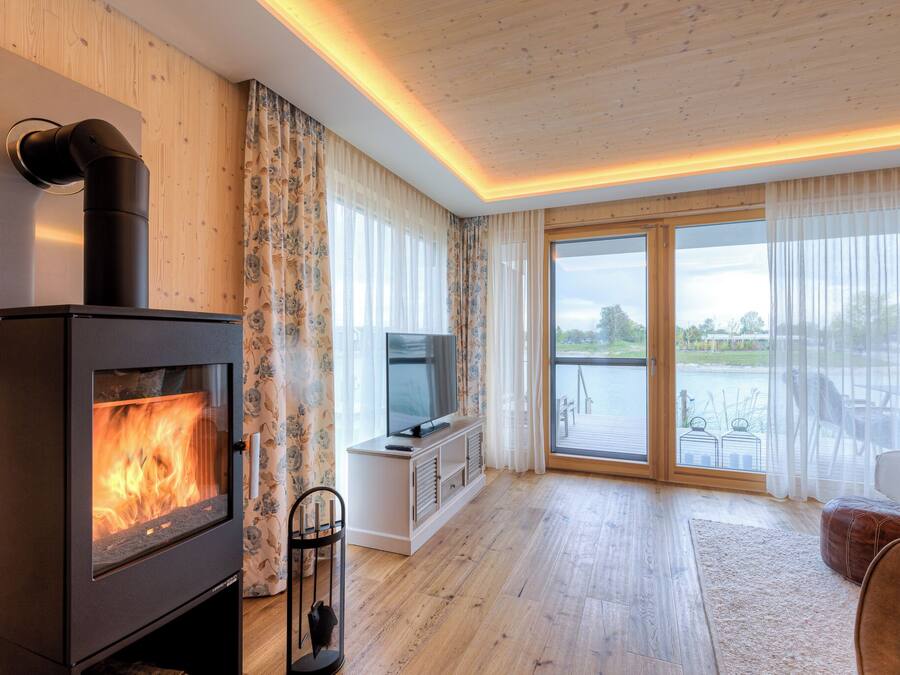 A modern living room with a wood-burning stove, a TV, and a large sliding glass door leading to an outdoor area.