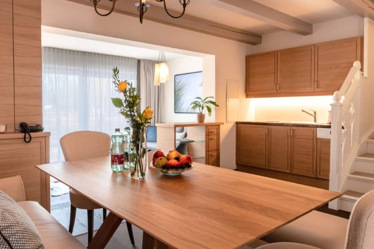 Een moderne keuken met houten kasten, een eettafel met stoelen en een schaal met fruit.