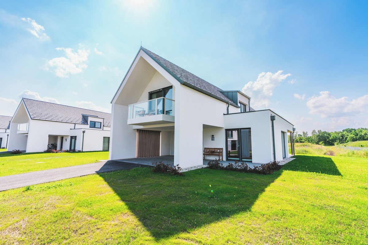 Een modern huis met twee verdiepingen, een balkon, oprit en een verzorgd gazon.