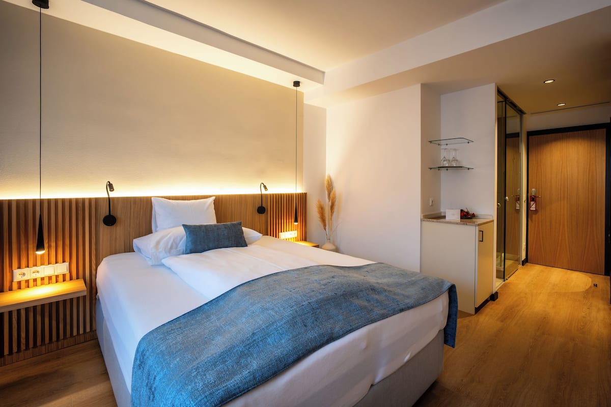 Een moderne slaapkamer met een groot bed, nachtkastjes, een nachtkast en een inbouw kast.