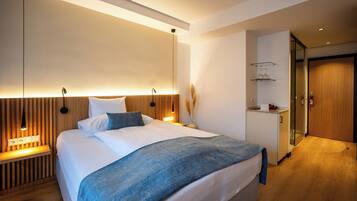 A modern bedroom with a large bed, bedside tables, a nightstand, and a built-in wardrobe.