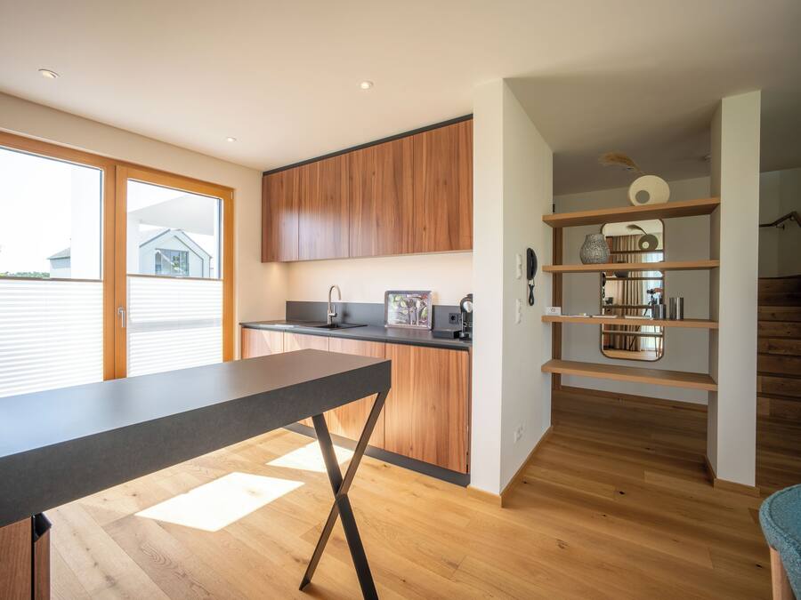 A modern kitchen with wooden cabinets, a black countertop, and a dining table.