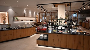 Une cuisine moderne avec des meubles en bois, un îlot central doté d’un appareil électroménager rouge, ainsi que divers ustensiles et appareils de cuisine.
