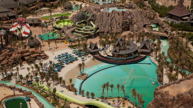 Een resort met een groot centraal zwembad, meerdere kleinere zwembaden en een waterglijbaan.