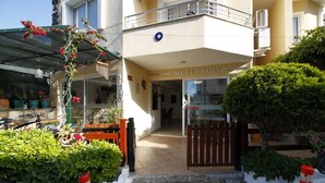 A hotel entrance with a reception area, a gated driveway, and potted plants.